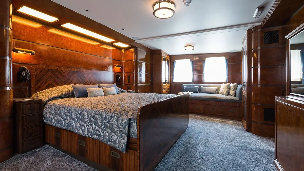 Mahogany panelled cabin bedroom with large wooden bed and headboard, built in lighting and window seat, Malahne